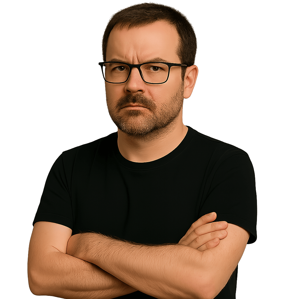 Yann Somou, self-confessed moany prick of an author and writer of 127 Reasons Why You Are an Idiot, standing with arms crossed in a black t-shirt, giving a serious, unimpressed look.